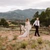 Bride and groom in wedding attire, a suit and boho wedding dress, walking through the park holding hands