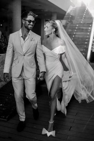 This dress rental is a dreamy off-the-shoulder wedding dress with a slit in front, made of crepe, a low back and cap sleeves
