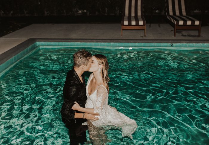 image of a bride and groom after they jump in the pool in their wedding attire at night