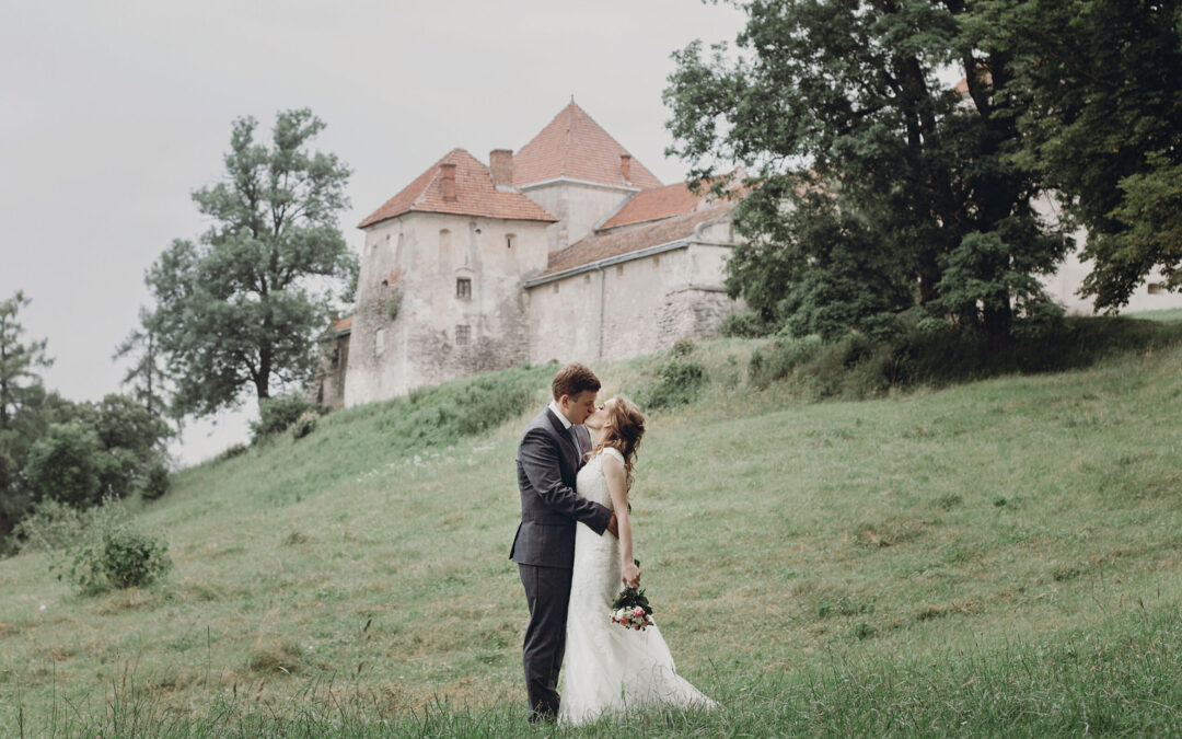 Inages of a bride and groom kissing in a field below a gorgeous house. 2025 wedding trends: micro-weddings, courthouse ceremonies and multi-day adventure elopements